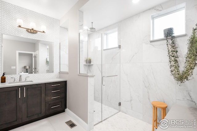 bathroom with a marble finish shower, baseboards, visible vents, and vanity