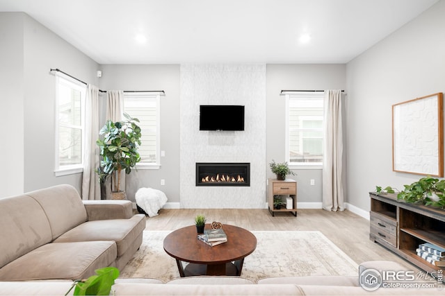 living room with baseboards, a large fireplace, recessed lighting, and light wood-style floors