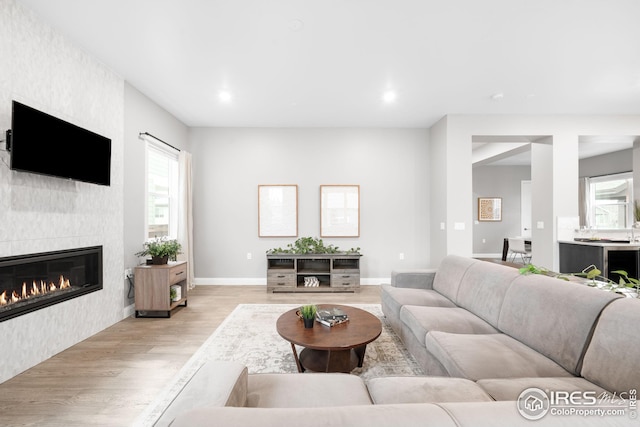 living room with baseboards, light wood-style floors, a tile fireplace, and recessed lighting