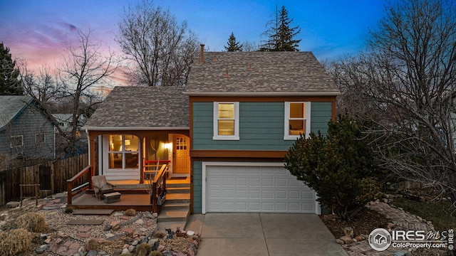 view of front of house with fence, a garage, driveway, and roof with shingles