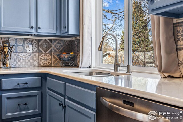 kitchen featuring a sink, blue cabinetry, tasteful backsplash, light countertops, and dishwasher