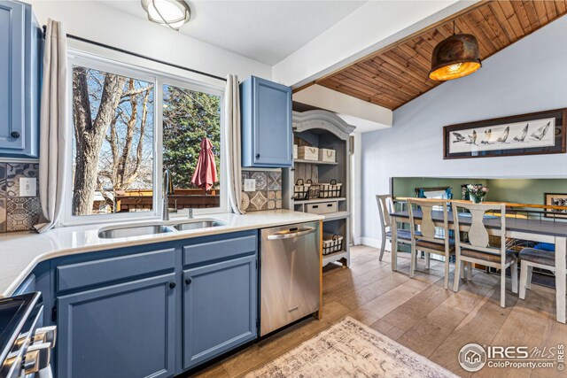 kitchen featuring appliances with stainless steel finishes, vaulted ceiling with beams, blue cabinets, and a sink