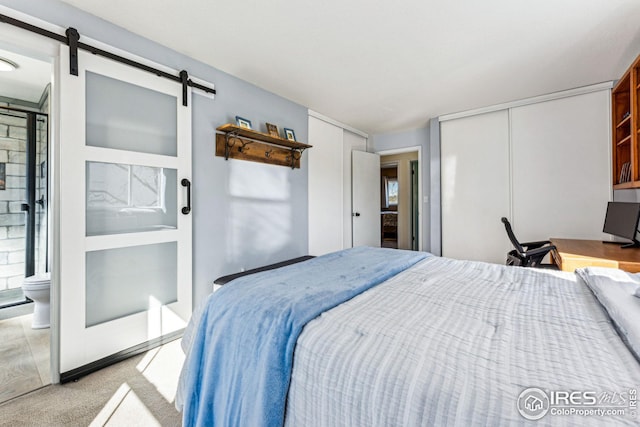 carpeted bedroom with a barn door and a closet