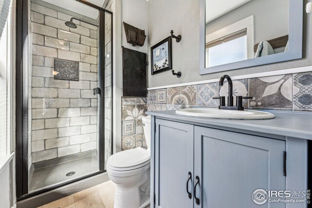 bathroom featuring toilet, a stall shower, and tile walls