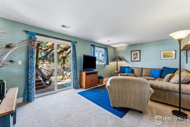 living area featuring visible vents, baseboards, a textured ceiling, and carpet flooring