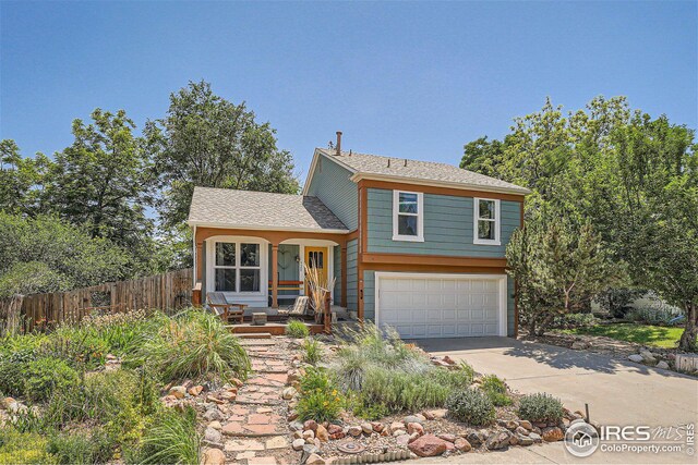 split level home featuring fence, a garage, and driveway