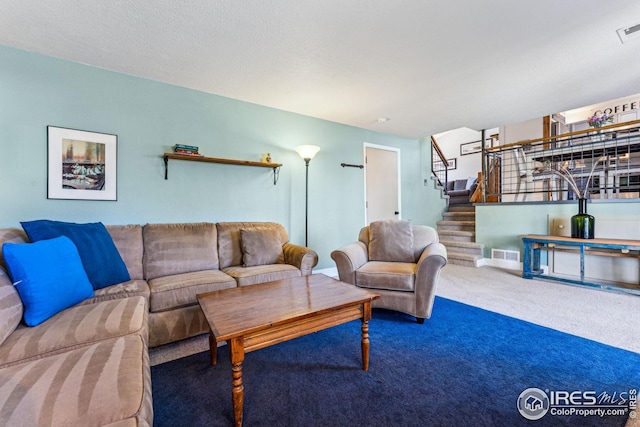 living room featuring visible vents, carpet, stairs, and a textured ceiling