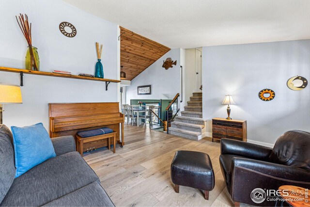 living area with baseboards, stairs, lofted ceiling, and wood finished floors