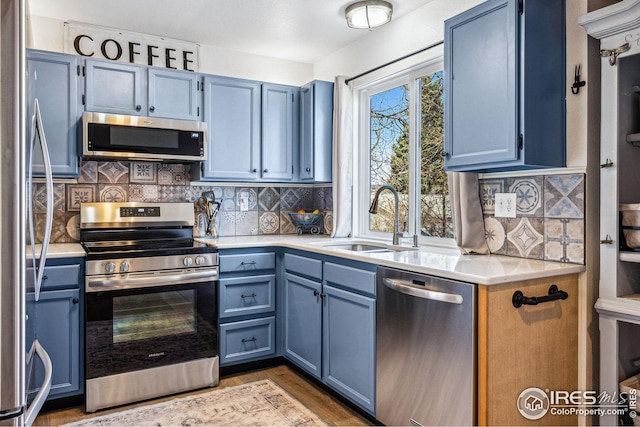 kitchen featuring a sink, light countertops, blue cabinets, and stainless steel appliances