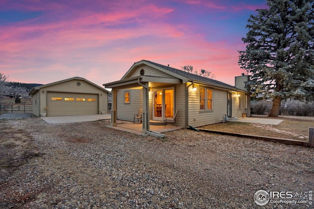 view of front of home with an outbuilding, a detached garage, fence, a chimney, and a patio area