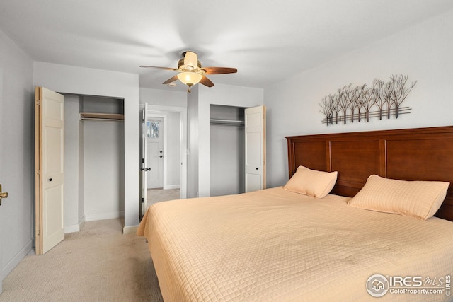 bedroom featuring multiple closets, light colored carpet, baseboards, and a ceiling fan