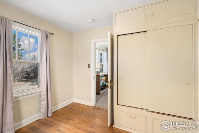 unfurnished bedroom with a closet, baseboards, and wood finished floors