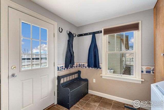 doorway with baseboards and dark tile patterned flooring