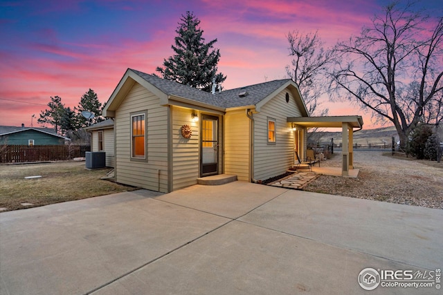 view of front of house featuring cooling unit, a patio area, driveway, and fence