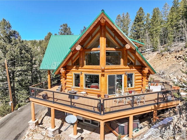 back of property with metal roof, a deck, and log siding