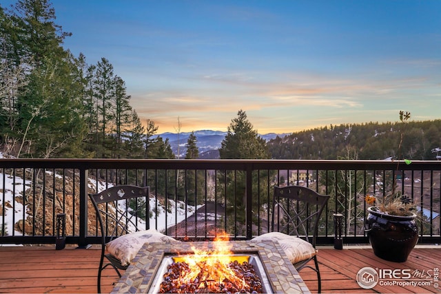 wooden terrace with an outdoor fire pit and a mountain view