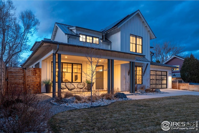 modern farmhouse with metal roof, a porch, fence, board and batten siding, and a standing seam roof