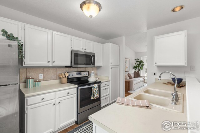 kitchen featuring stainless steel appliances, a sink, light countertops, and white cabinets