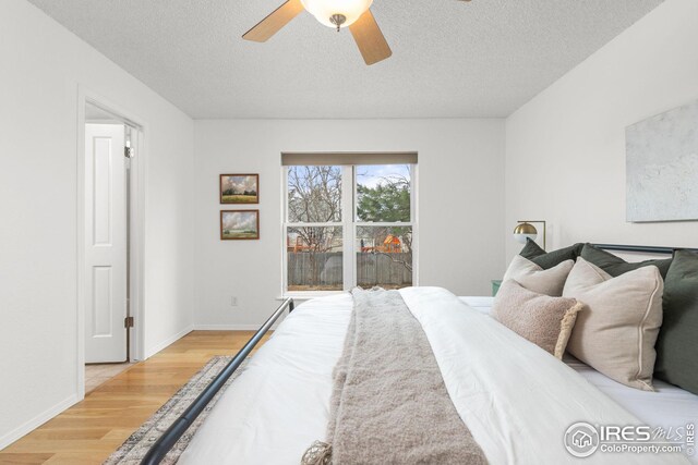 bedroom with a textured ceiling, ceiling fan, light wood-style flooring, and baseboards