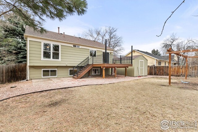 rear view of house with fence private yard, stairway, a storage unit, and an outbuilding