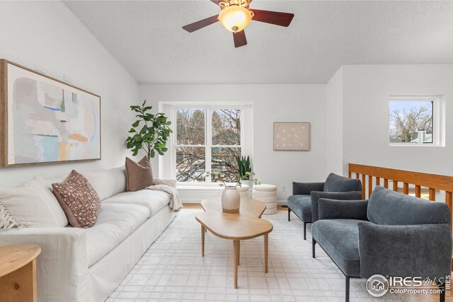 living room featuring a ceiling fan, a textured ceiling, and light floors