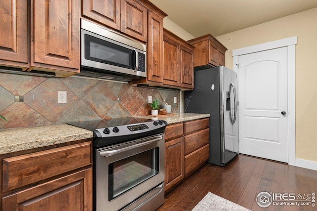 5850 Dripping Rock Ln, Fort Collins, CO 80528 - kitchen featuring dark wood finished floors, decorative backsplash, appliances with stainless steel finishes, brown cabinetry, and baseboards