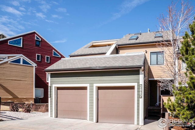 view of front of property with driveway, a shingled roof, and an attached garage