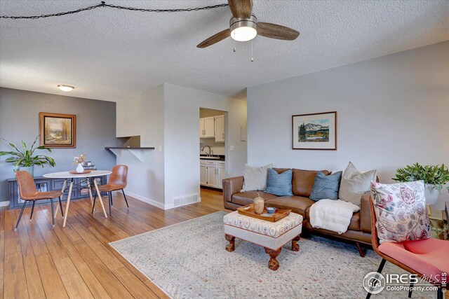 1105 Bacchus Dr Unit 8, Lafayette, CO 80026 - living area with visible vents, light wood-style floors, a ceiling fan, a textured ceiling, and baseboards