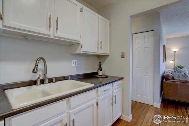 1105 Bacchus Dr Unit 8, Lafayette, CO 80026 - kitchen with dark countertops, white cabinetry, a sink, and light wood finished floors