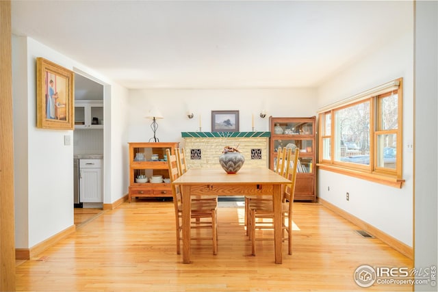 dining room featuring light wood finished floors, baseboards, and visible vents