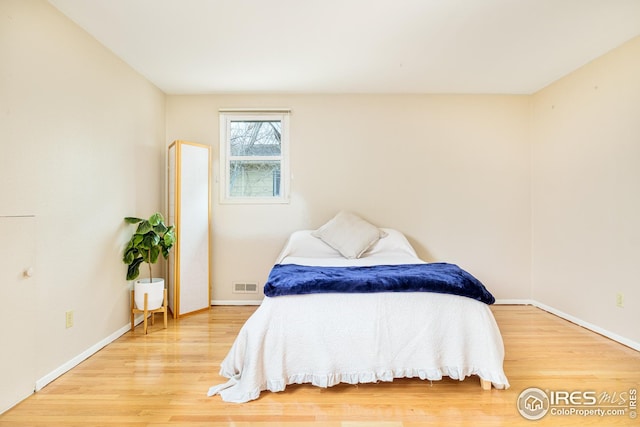 bedroom featuring light wood-style floors, visible vents, and baseboards