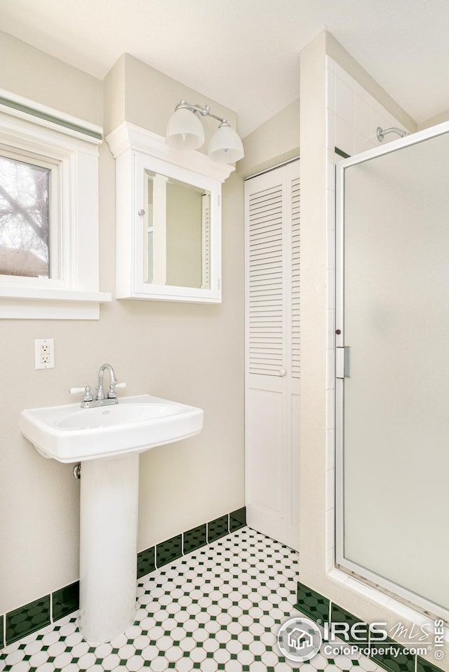 bathroom featuring a sink, a shower stall, and baseboards