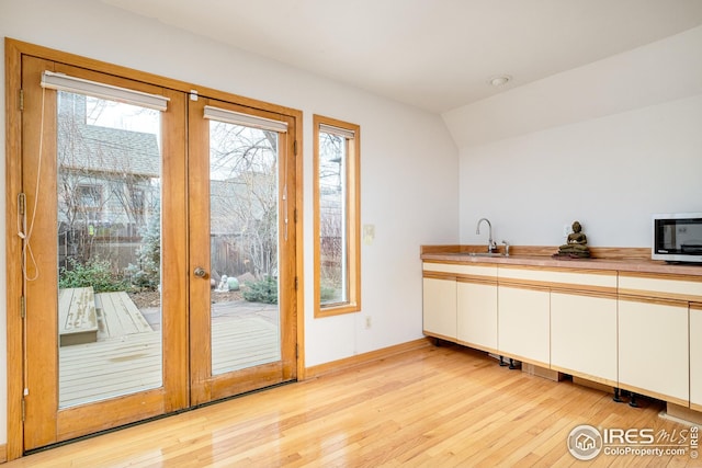 kitchen with light wood-style floors, french doors, stainless steel microwave, and a sink