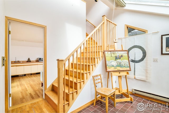 stairs with a baseboard heating unit and wood finished floors
