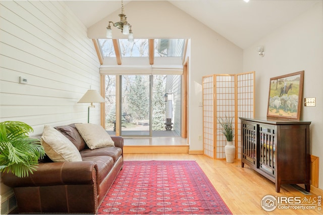 living room with high vaulted ceiling, wood finished floors, and a notable chandelier