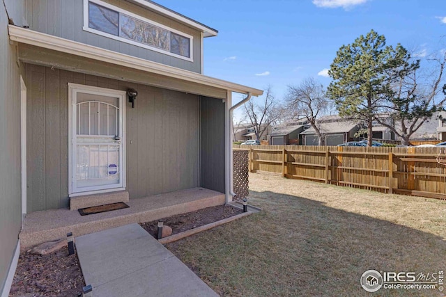 view of exterior entry featuring a yard and fence