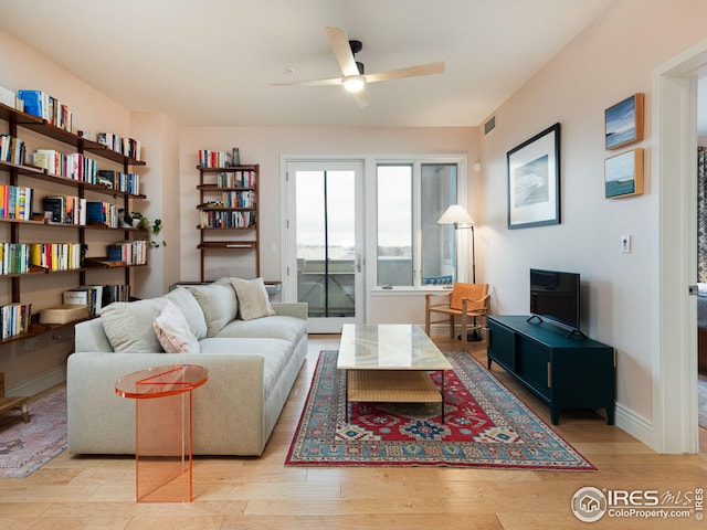 living area with visible vents, a ceiling fan, light wood-type flooring, and baseboards