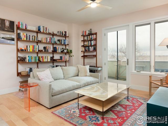 living area with ceiling fan, baseboards, and light wood-style floors