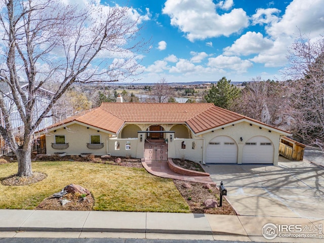 mediterranean / spanish home featuring a fenced front yard, a tiled roof, stucco siding, driveway, and a gate