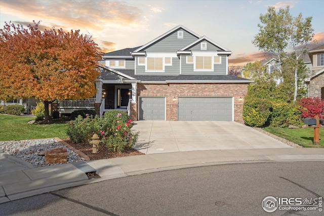 view of front of home featuring a shingled roof, concrete driveway, a front lawn, a garage, and brick siding