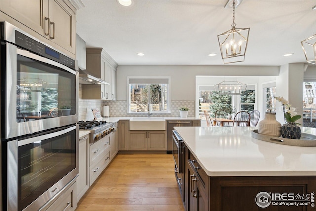 kitchen featuring stainless steel appliances, light countertops, an inviting chandelier, and a sink