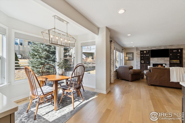 dining room with recessed lighting, a tile fireplace, light wood-type flooring, and baseboards