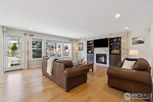 living area with built in shelves, baseboards, light wood-style flooring, recessed lighting, and a large fireplace