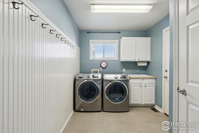 laundry room with visible vents, a sink, washing machine and dryer, cabinet space, and baseboards