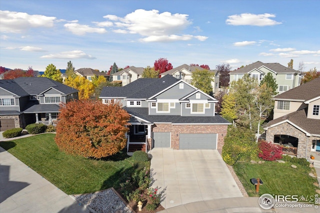 view of front facade featuring brick siding, a front lawn, a residential view, concrete driveway, and an attached garage