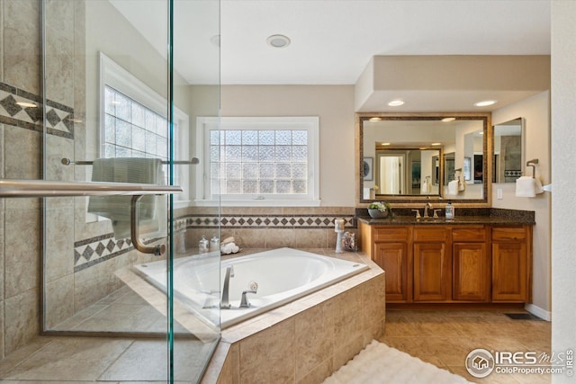 full bathroom featuring tile patterned floors, a jetted tub, vanity, and a tile shower