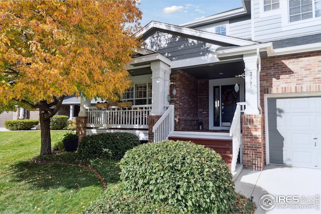 property entrance with brick siding, covered porch, a lawn, and a garage