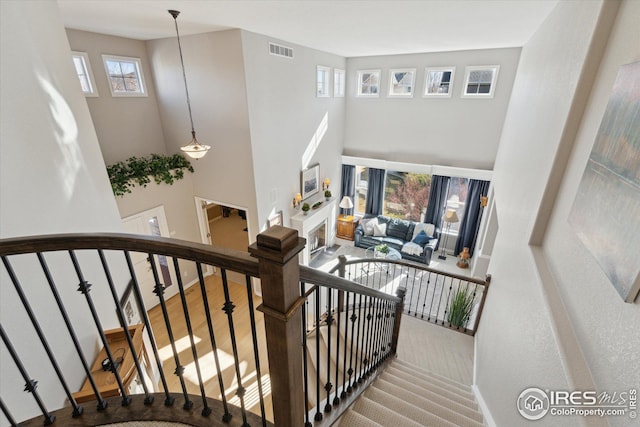 staircase featuring visible vents, a high ceiling, and baseboards