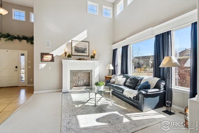 living area featuring visible vents, a fireplace, baseboards, and a towering ceiling