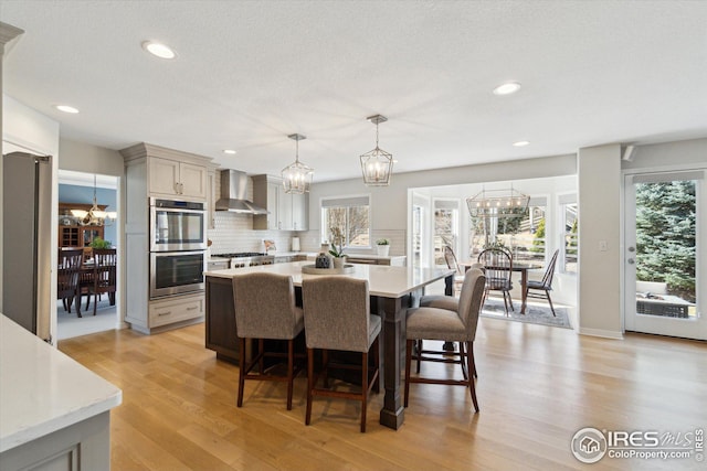 dining area with an inviting chandelier, light wood-style flooring, recessed lighting, and a textured ceiling